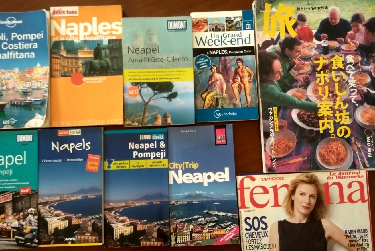 Una selezione di guide turistiche e una rivista con diverse città e temi.