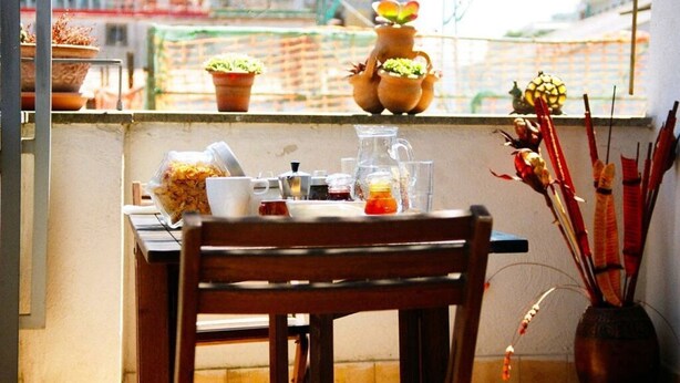 A balcony with a table, potted plants, and a vase with flowers. - Sui Tetti di Napoli - panoramic terrace 2 (Napoli)