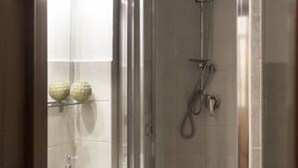 A shower with a glass door, a handheld showerhead, and a towel rack with two towels. - Sui Tetti di Napoli - in the heart of authentic naples (Napoli)