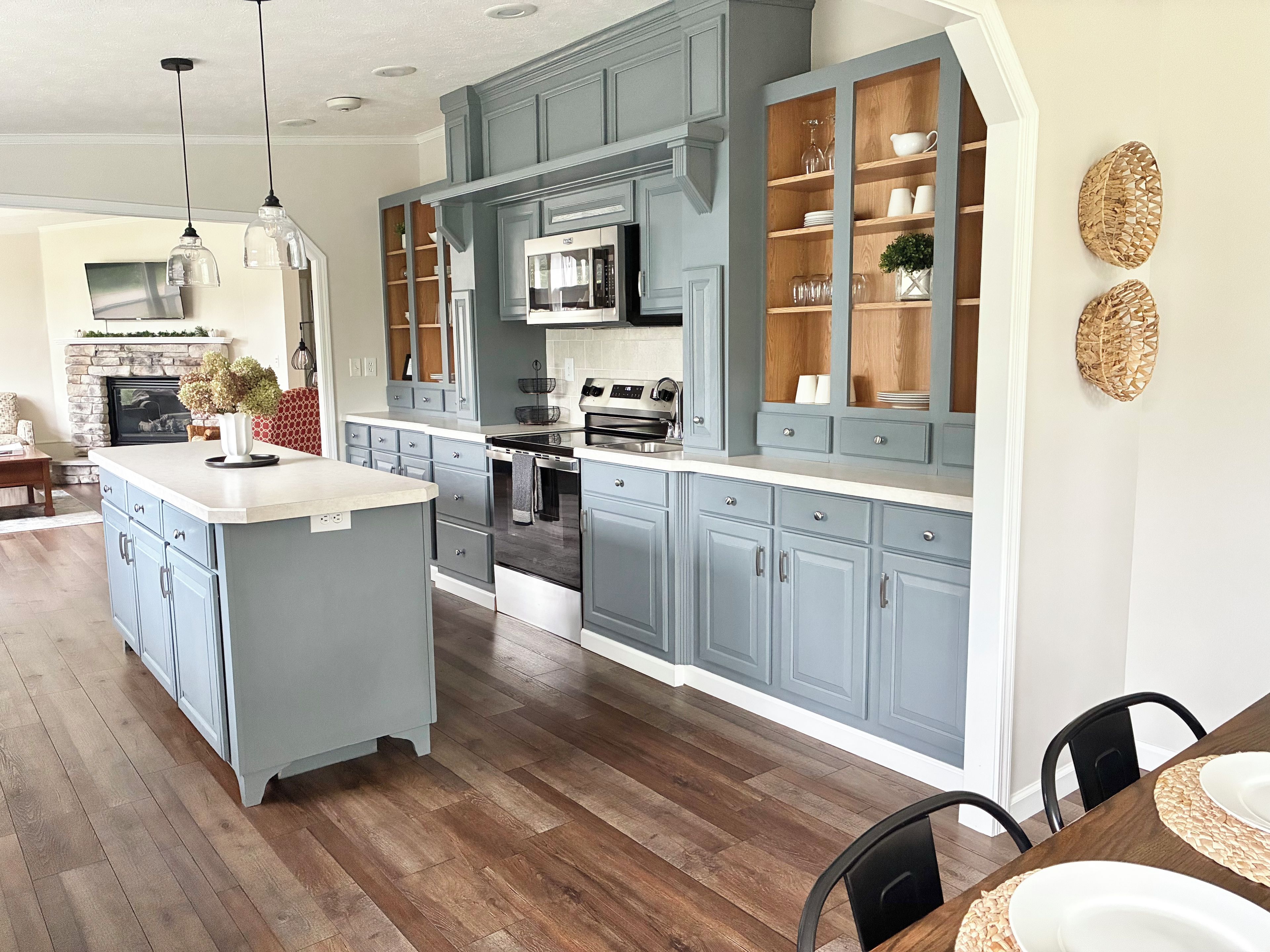 A modern kitchen with grey cabinets, a central island, and wooden flooring.