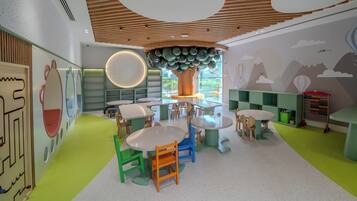 A children's play area with round tables, chairs, and a large tree-like structure.
