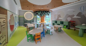 A children's play area with round tables, chairs, and a large tree-like structure.