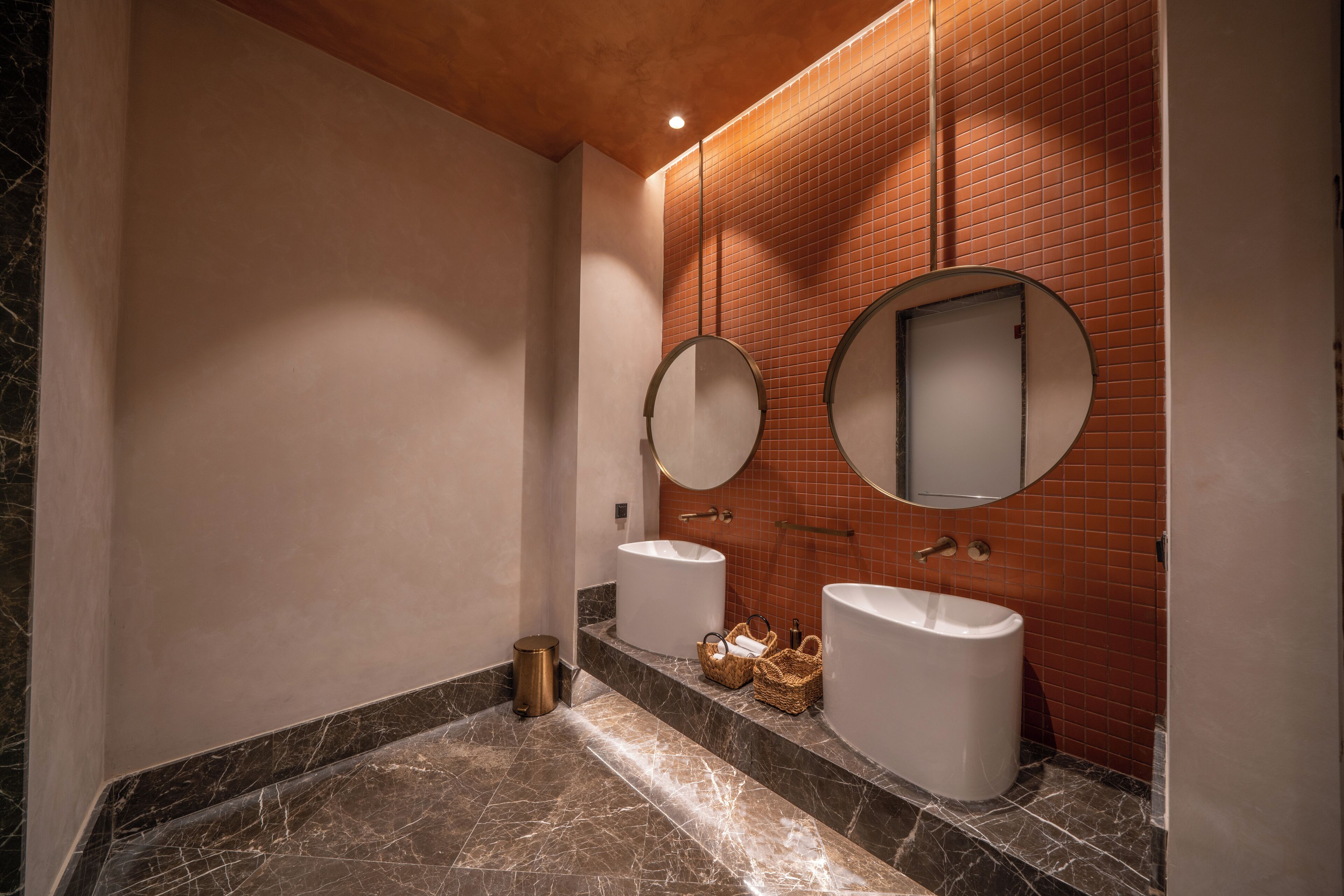 Un baño con dos lavamanos, un espejo y un cubo de basura.