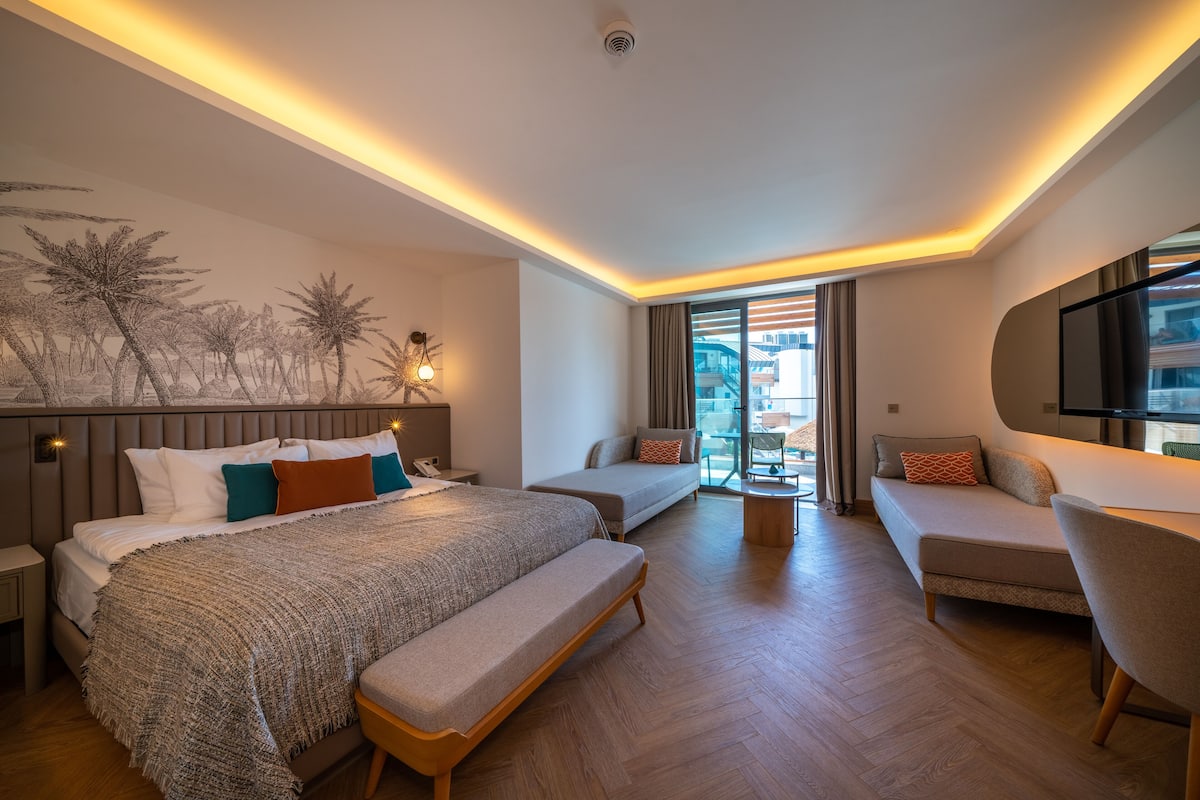 Une chambre d’hôtel moderne dotée d’un grand lit, d’un canapé, d’un fauteuil et d’un balcon avec vue.