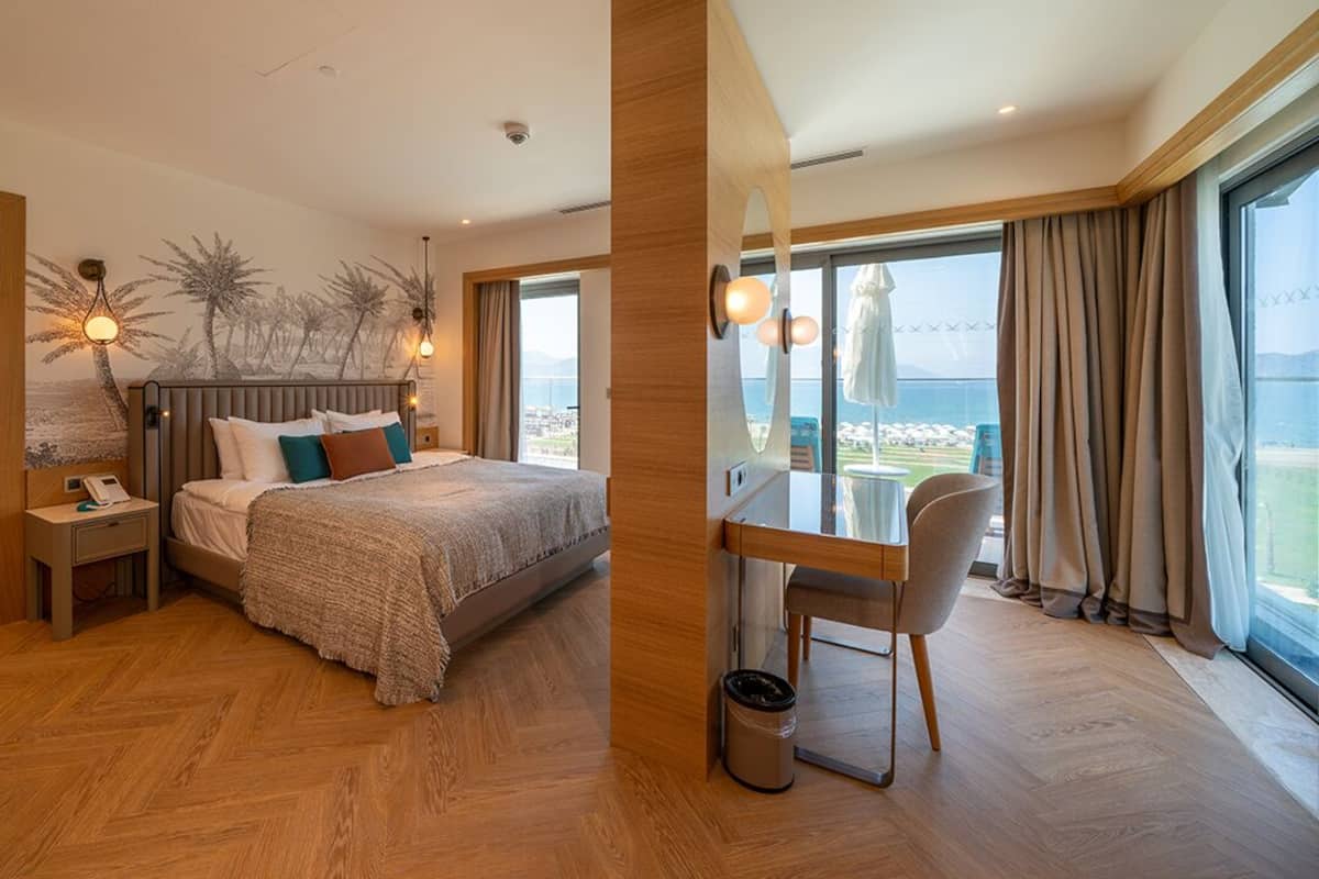 Une chambre spacieuse avec un grand lit, un bureau et une vue sur la mer.