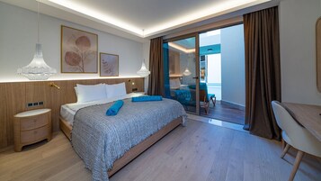 A modern hotel room with a large bed, a desk, and a view of the outdoor area.