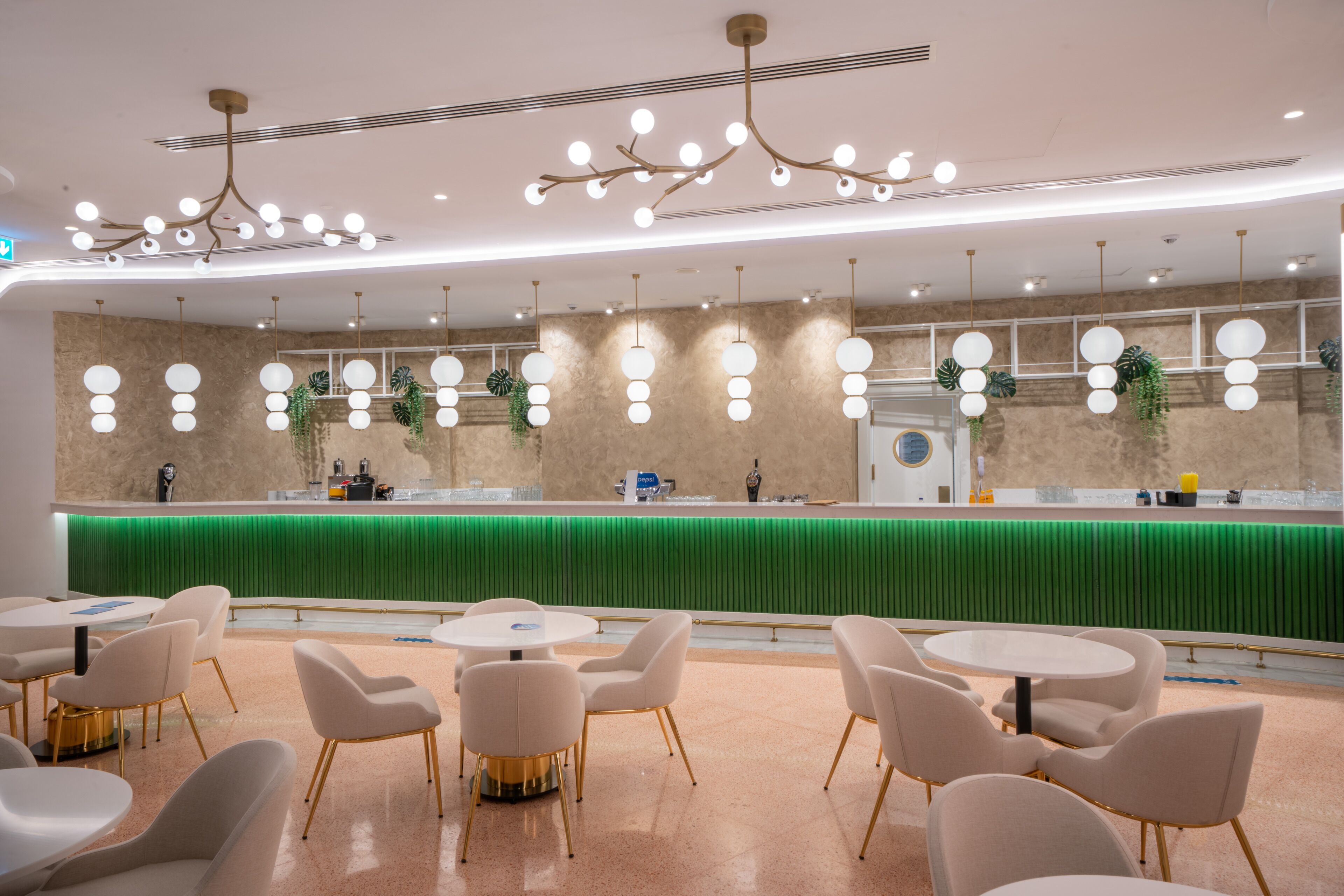 A modern restaurant with a green counter, white chairs, and pendant lighting.