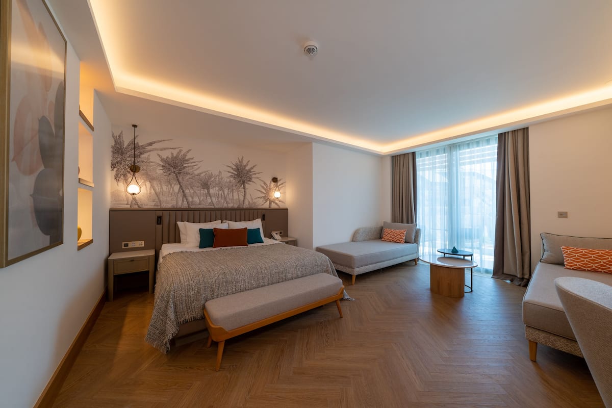 Une chambre d’hôtel moderne avec un grand lit, un canapé, un banc et une petite table.