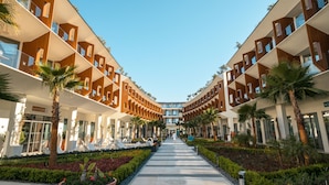 A modern hotel with a central corridor flanked by balconies and palm trees.