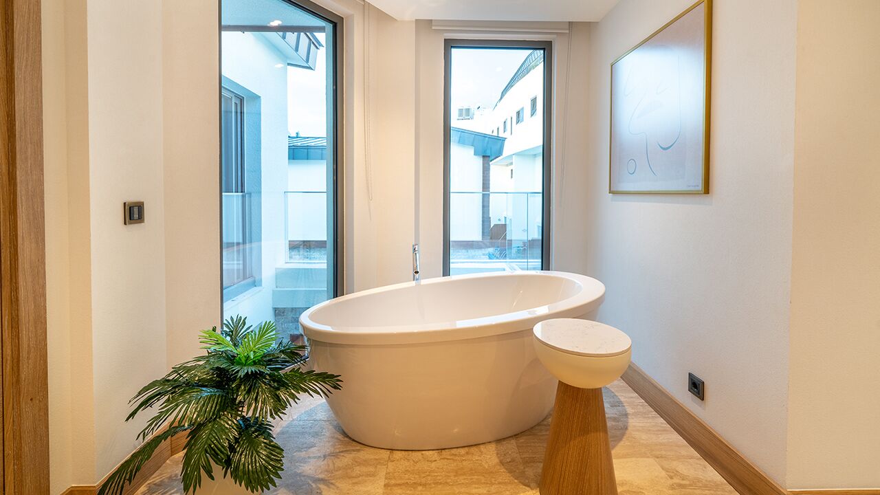 Un baño moderno con una bañera independiente, un inodoro y una planta en maceta.