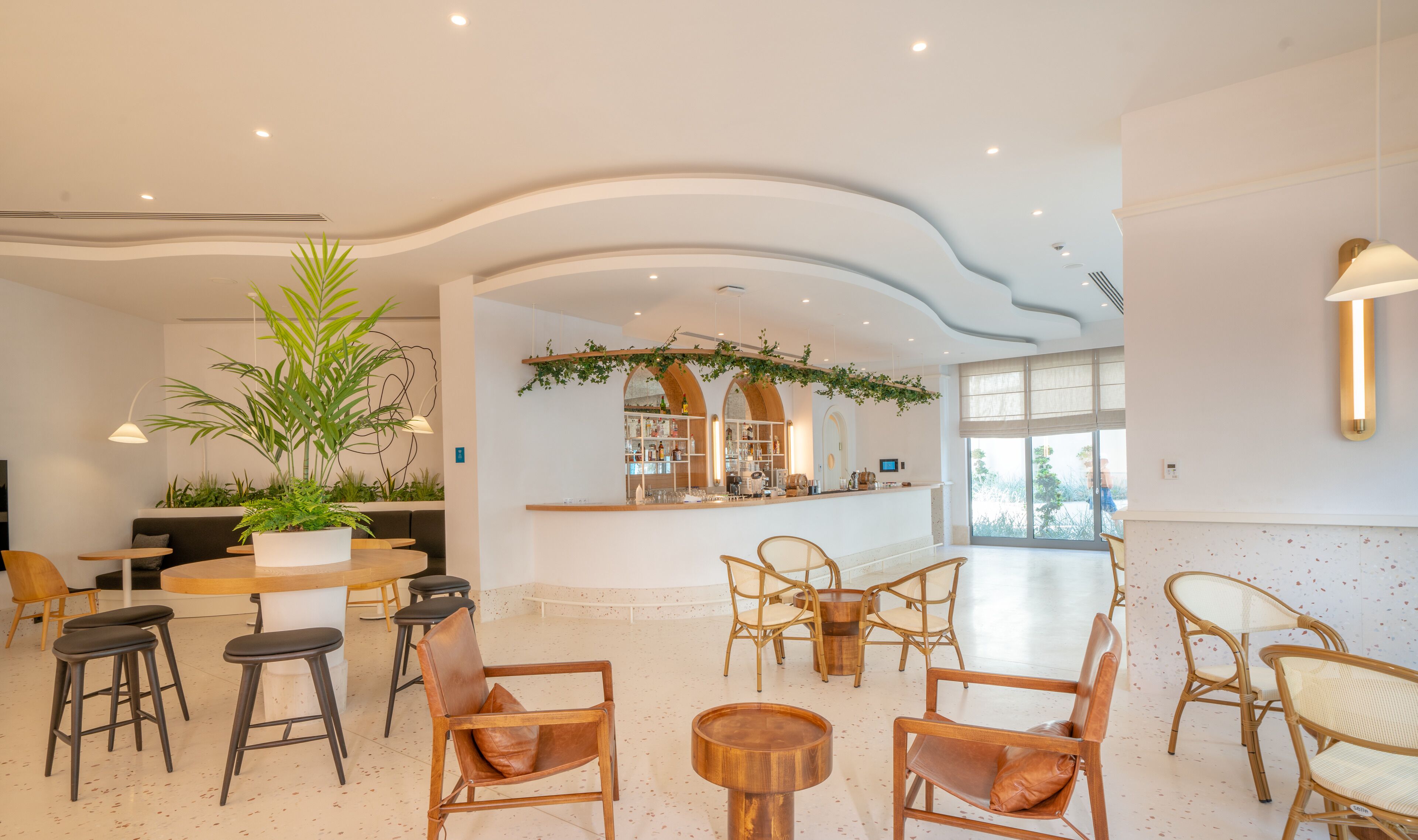 A spacious lobby with a bar area, seating arrangements, and a large potted plant.