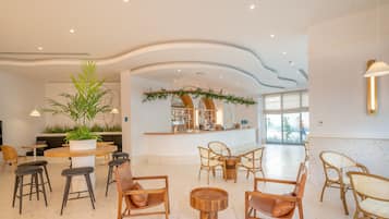A spacious lobby with a bar area, seating arrangements, and a large potted plant.
