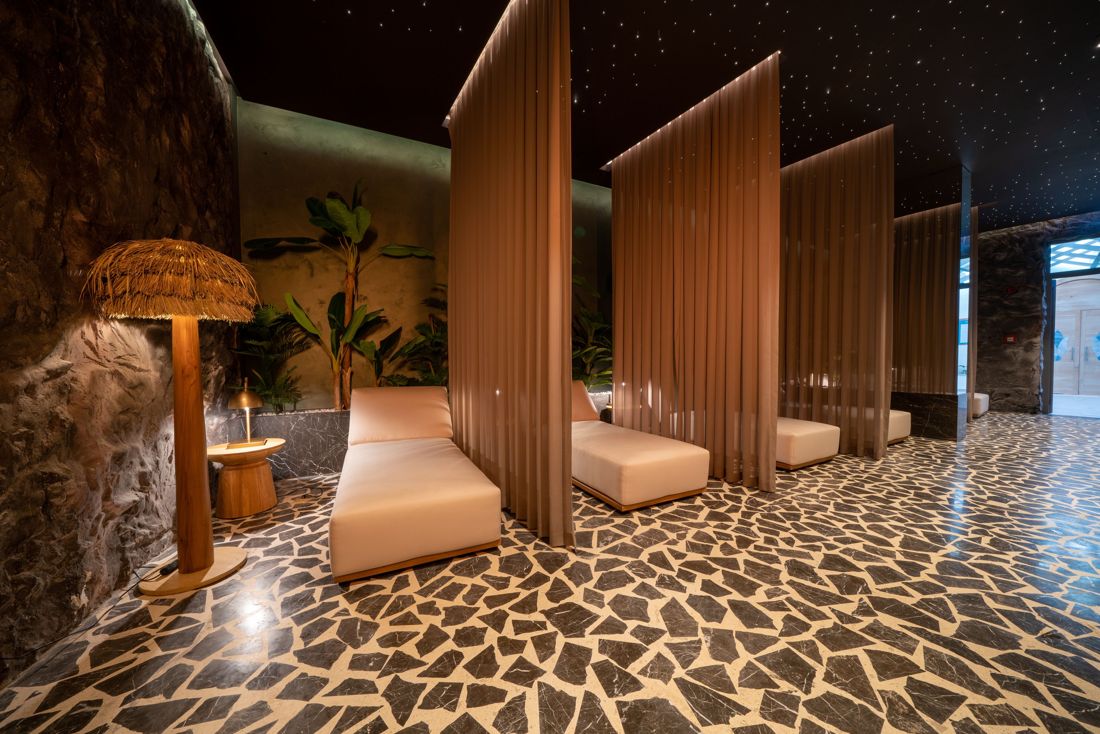 A modern spa area with a mosaic floor, cushioned seating, and a starry ceiling.