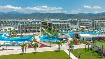 Un complexe hôtelier doté de plusieurs piscines, de palmiers et offrant une vue sur un paysage montagneux.