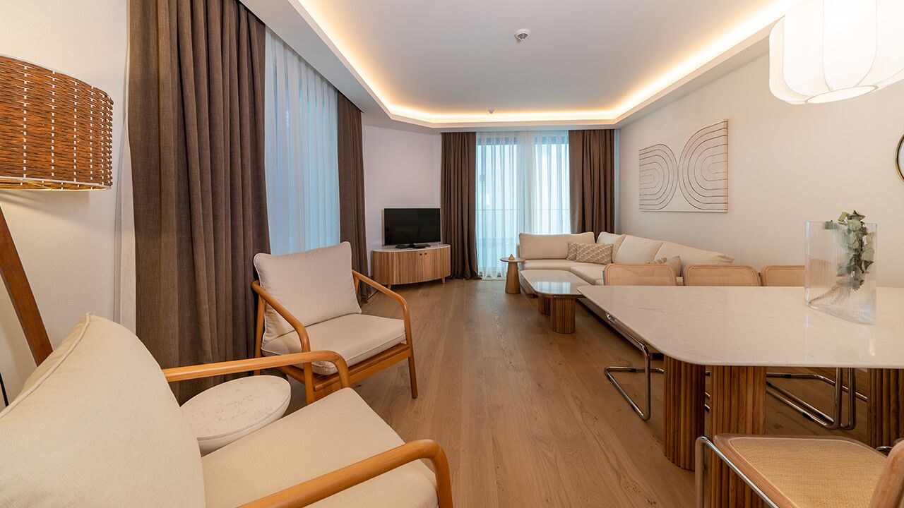 A modern living room with a sofa set, a dining table, and a TV.