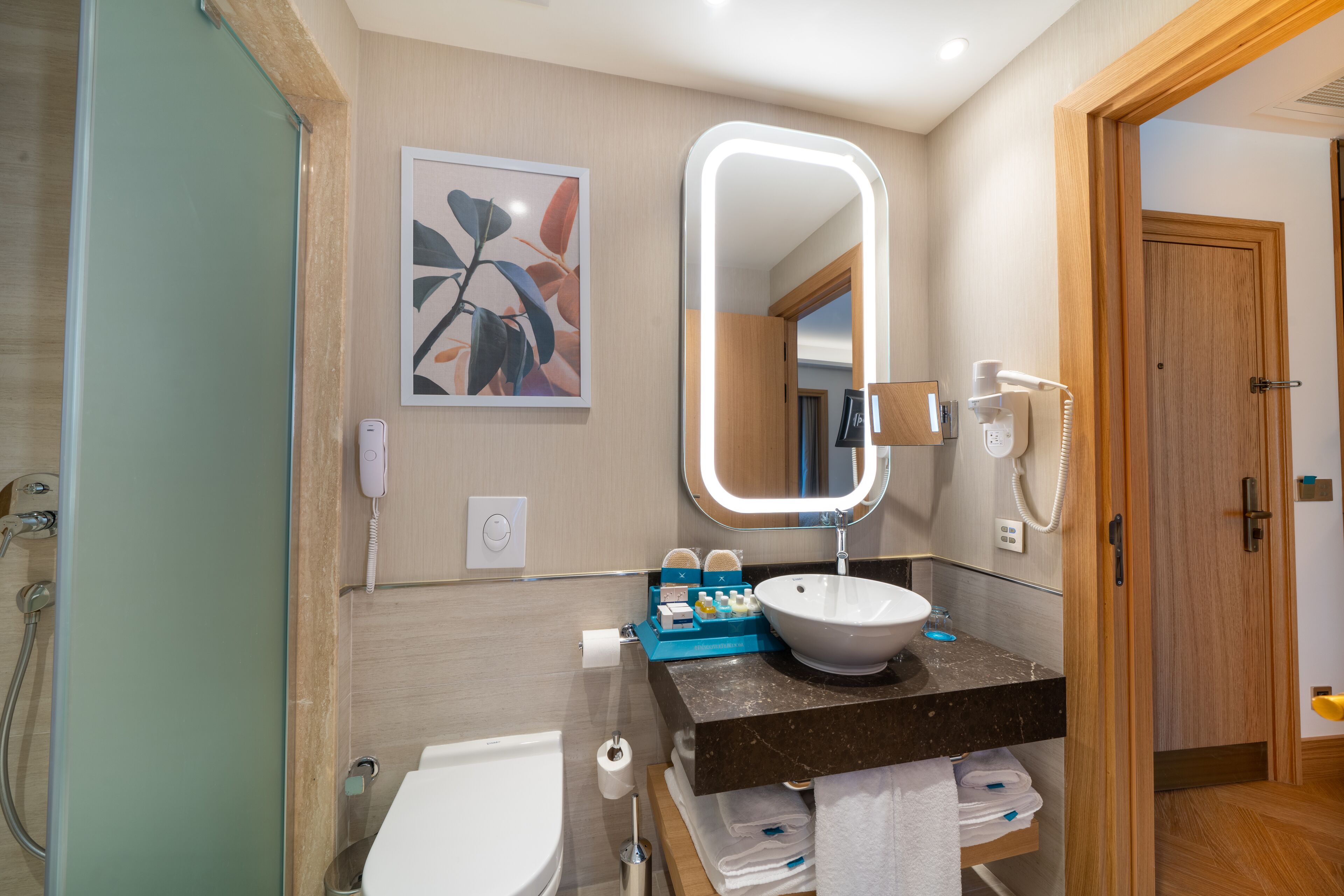 A modern bathroom with a white sink, a large mirror, and a shower.