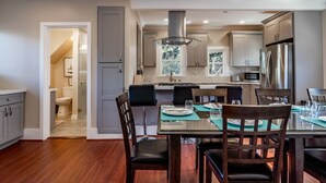 Una cocina moderna con una isla central, electrodomésticos de acero inoxidable y una zona de comedor con mesa de vidrio y sillas.