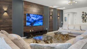 Un salon moderne avec un grand téléviseur à écran plat, un canapé et une table basse.