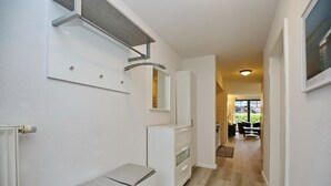 Ein Flur mit einer Bank, einem weißen Schrank und einem Spiegel.