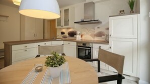 Eine moderne Küche mit weißen Schränken, einer Holz-Kochinsel und einer Pendelleuchte.