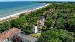 Luftaufnahme einer Küstenstadt mit Strand, dichter Vegetation und traditioneller Architektur.