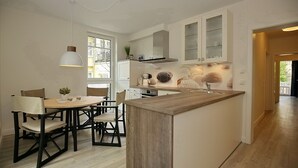 Cozinha moderna com ilha central, armários brancos e área de jantar com cadeiras.