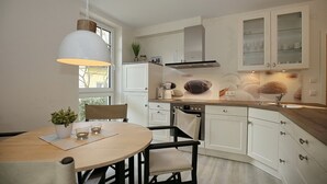 Cozinha moderna com armários brancos, bancada de madeira e luminária pendente.