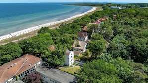 Vista aérea de un pueblo costero con playa, vegetación densa y arquitectura tradicional.