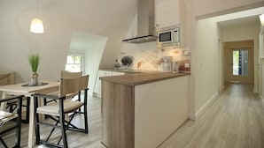 Una cocina moderna con una isla central, un comedor con sillas e iluminación colgante.