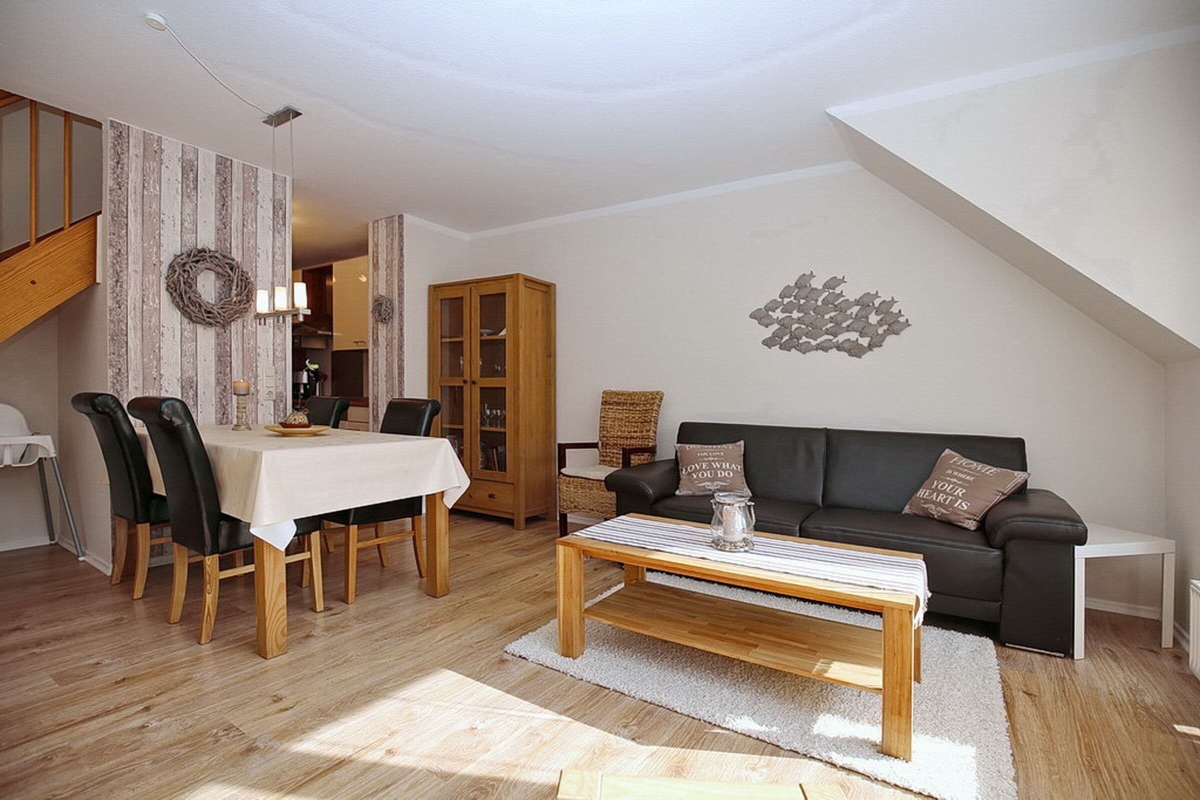 Una sala de estar acogedora con comedor, un sofá de cuero negro, muebles de madera y un adorno en la pared.
