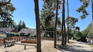Zona exterior delimitada amb seients, arbres i un parc infantil.