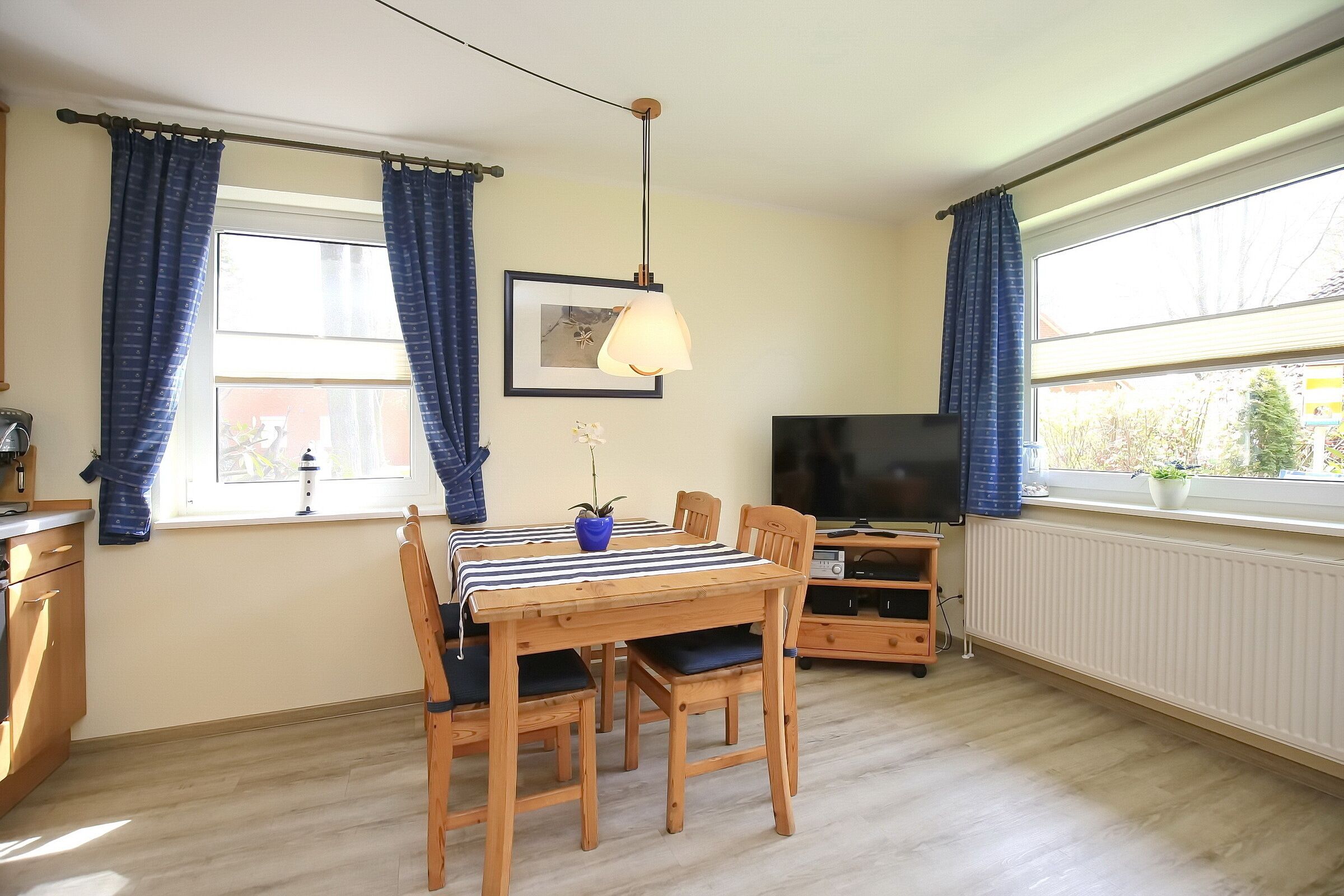 Un comedor con una mesa y sillas de madera, un televisor y una ventana con cortinas.