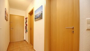 Ein Korridor mit Holztüren, Fliesenboden und Wandbildern.