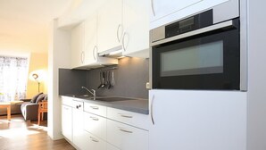 Une cuisine moderne avec des armoires blanches, un four en acier inoxydable et un micro-ondes encastré.