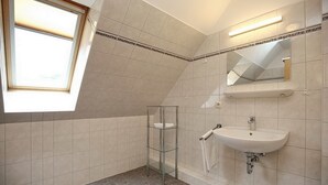 Een moderne badkamer met dakraam, glazen plank, wastafel en spiegel.