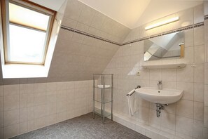 Un baño moderno con tragaluz, repisa de vidrio, lavamanos y espejo.