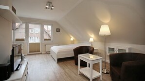 Een slaapkamer met een bed, een bureau, een stoel en een lamp.