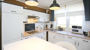 Une cuisine moderne avec des meubles blancs, un plan de travail noir et deux suspensions lumineuses.