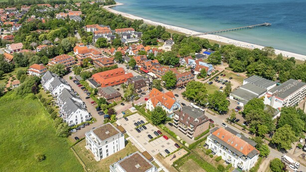 Vista aérea de un pueblo costero con edificios residenciales, una playa y un muelle.