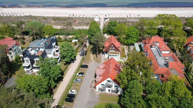 Vista aérea de una zona residencial costera con casas, una playa y cielo despejado.