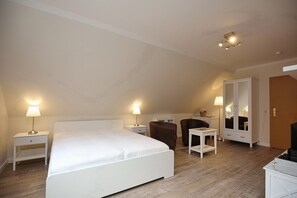 A bedroom with a large bed, two bedside tables with lamps, a wardrobe, and a television.