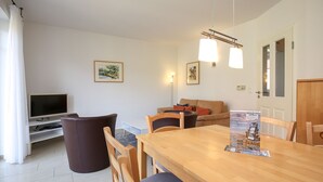 Een moderne woonkamer met een houten eettafel, een bank en een televisie.