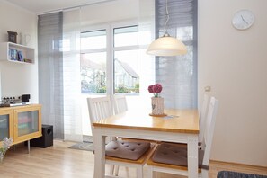 Ein Essbereich mit Holztisch, weißen Stühlen und einer Pendelleuchte.