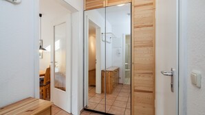 A modern interior with a wooden door, a bench, and a tiled floor. - Dünenblick Wohnung 19 (Ostseebad Boltenhagen)