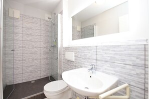 Un baño moderno con cabina de ducha de vidrio, lavabo blanco y un inodoro.