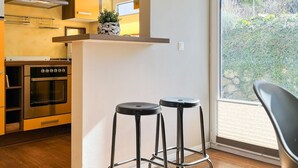 Une cuisine moderne dotée d’un four encastré, d’une cuisinière et d’une grande fenêtre.