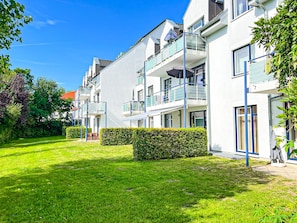Ein modernes Apartmenthaus mit Balkonen, einem gepflegten Rasen und blauem Himmel.