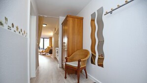 Een gang met een houten stoel, een kast en een wand met decoratieve details.