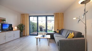 Een moderne woonkamer met een bank, een salontafel, een televisie en een vloerlamp.