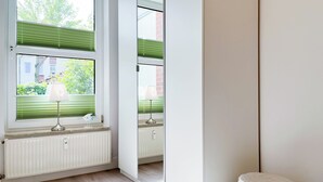 Una habitación moderna con un ventanal grande, un radiador y un taburete pequeño y redondo.